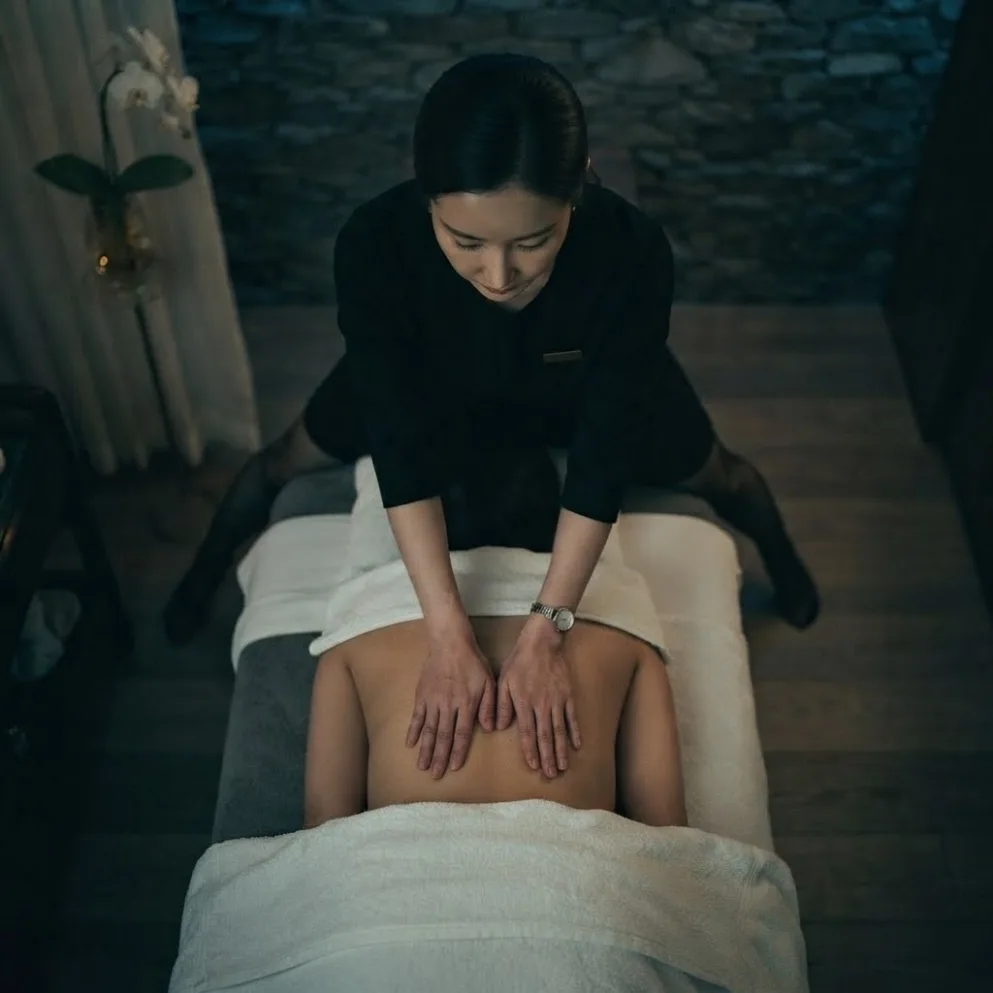 Therapist working on a guest’s back in a softly lit massage room